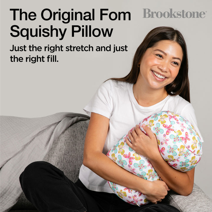 Woman holding a squishy pillow with text about the Original Fom Squishy Pillow by Brookstone.