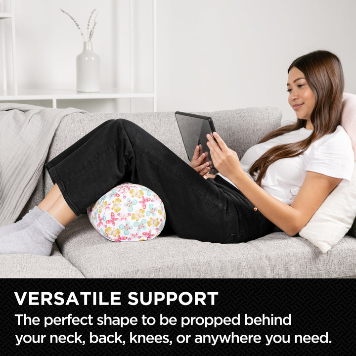 Woman sitting on a couch using a floral rolled-up towel for support.