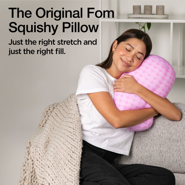 Woman hugging a pink squishy pillow with text about the product.