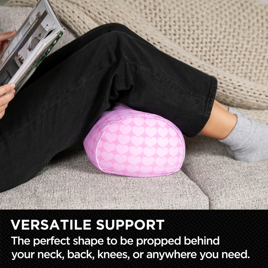 Person using a pink oval cushion for support on a couch with text 'VERSATILE SUPPORT'.