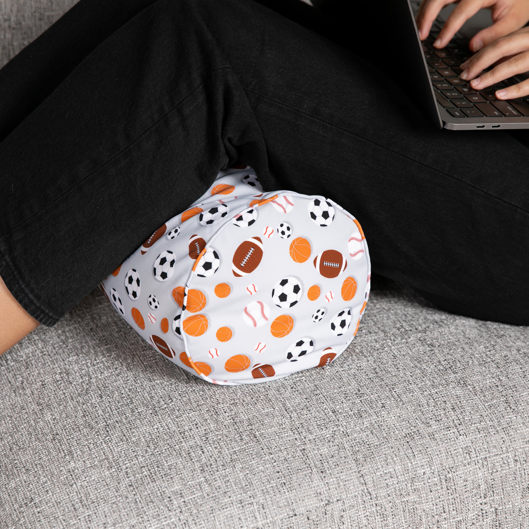 Person wearing patterned leg warmers sitting on a couch using a laptop.
