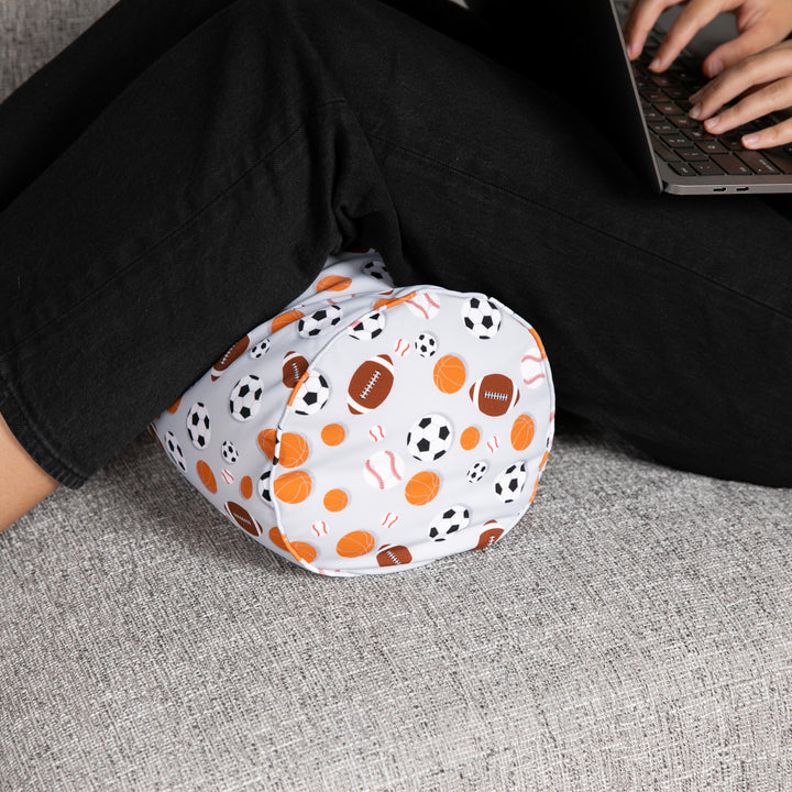 Person wearing patterned leg warmers sitting on a couch using a laptop.