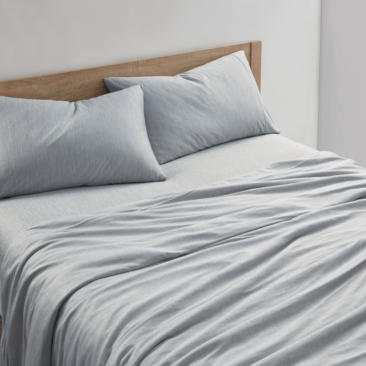 Gray bedding set on a bed with a wooden headboard.