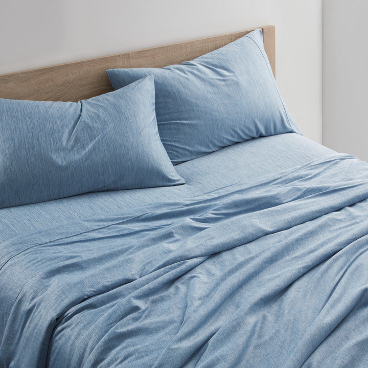 Blue denim-style bedding set on a bed with a wooden headboard.