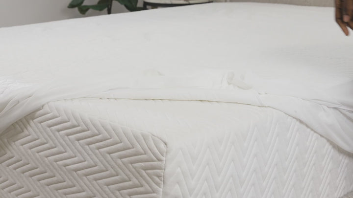 Video showcasing Soft white matress protector displayed on a neatly made bed in a bright, modern bedroom, showing its oversized design and cozy texture.