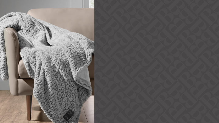 Video showing a plush heated throw draped over a beige armchair next to the text ‘Brookstone Heated Luxe Throw.