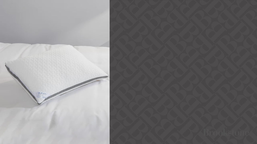 Video of a woman peacefully sleeping on a white textured Brookstone pillow with a gray accent stripe in a softly lit bedroom.