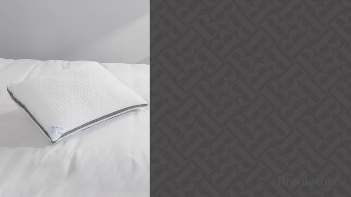 Video of a woman peacefully sleeping on a white textured Brookstone pillow with a gray accent stripe in a softly lit bedroom.
