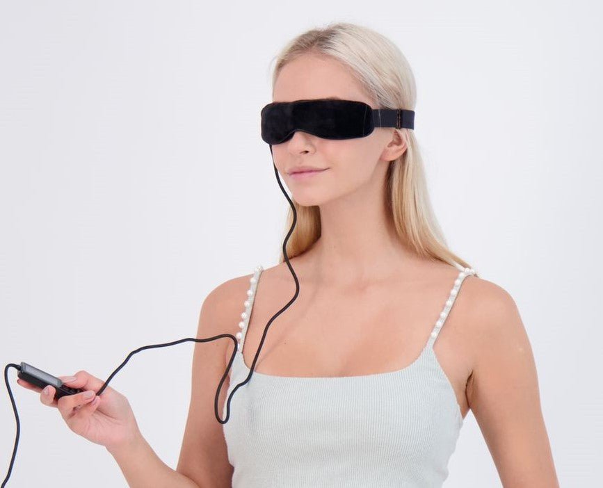 Woman using Wizard Research electric heated dry eye relief mask with handheld controller