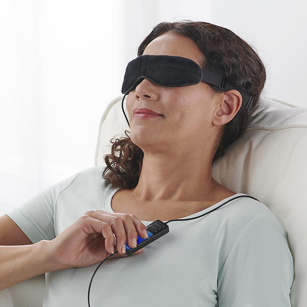 Woman using Wizard Research heated dry eye relief mask with handheld remote control